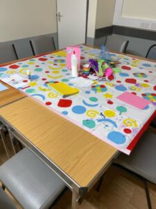Tables put together and covered with a multi-coloured protector